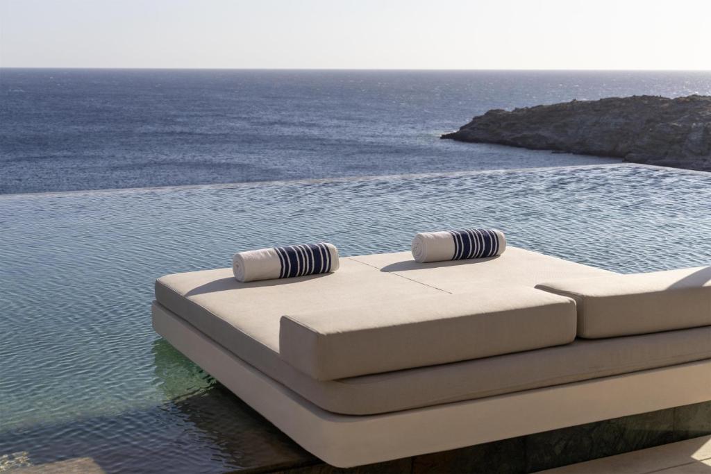 a bed with two pillows sitting on top of the water at One&Only Kéa Island in Pisses