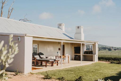 a white house with a table and chairs on a patio at Vleidam Guest Farm in Koringberg