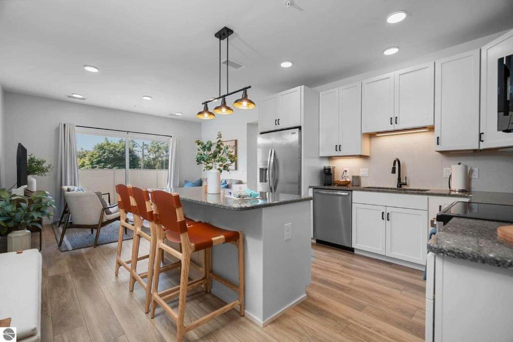 a kitchen with white cabinets and a table and chairs at 1 Block to Beach | Bikes, Wellness & More in Traverse City