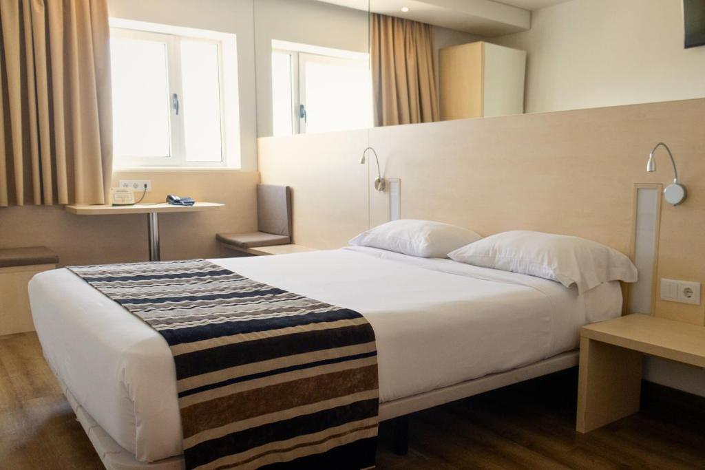 a hotel room with a large white bed with two pillows at Park Hotel Porto Valongo in Valongo