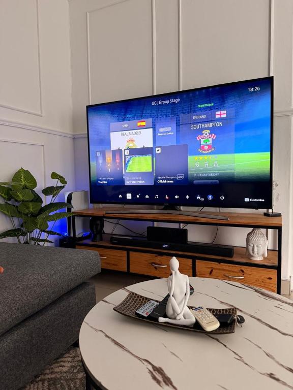 a living room with a large television and a table at Demmys Comfort in Cape Town
