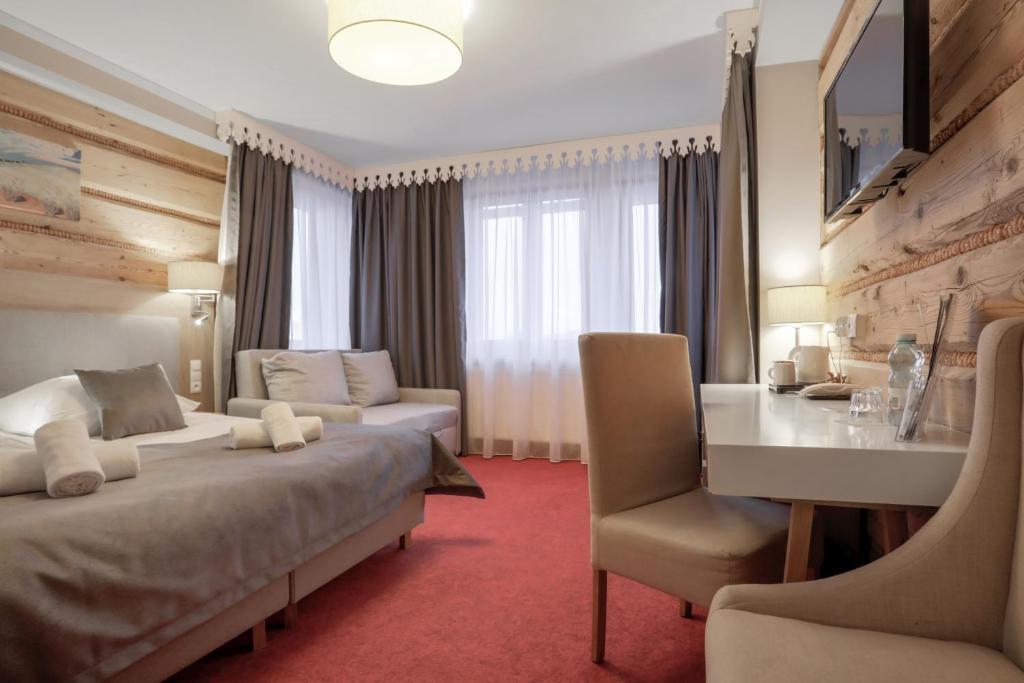 a hotel room with two beds and a desk at HOTEL*** NAT Bukowina Tatrzańska in Bukowina Tatrzańska