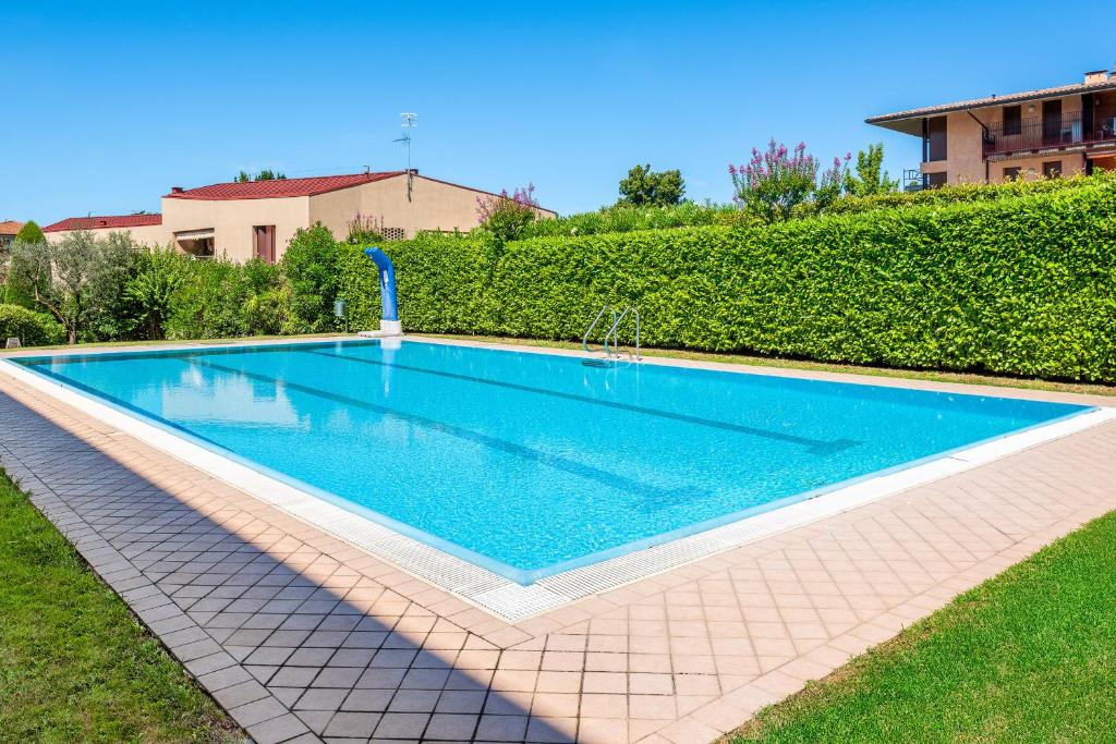 a swimming pool in a yard next to a hedge at Giardinello Apartments in Bardolino