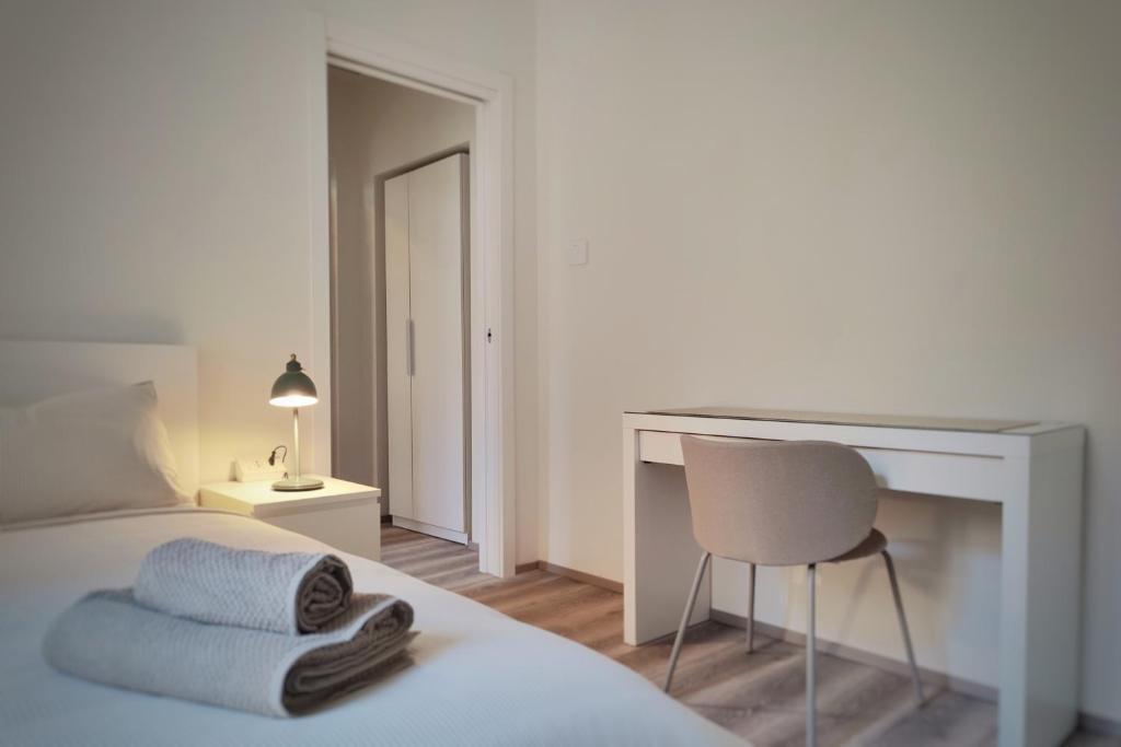 a bedroom with a bed and a desk and a chair at Otto Violini - City Center in Cremona