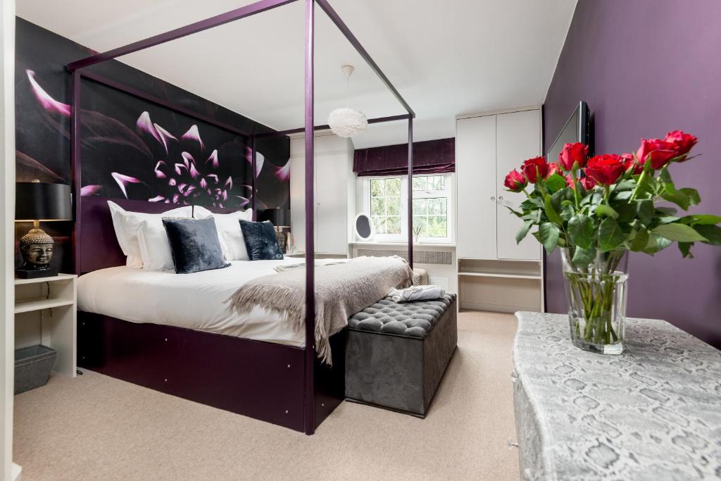 a bedroom with a canopy bed with a vase of red roses at LUXURIOUS Country Rooms in Hurley - THE FOX in Hurley
