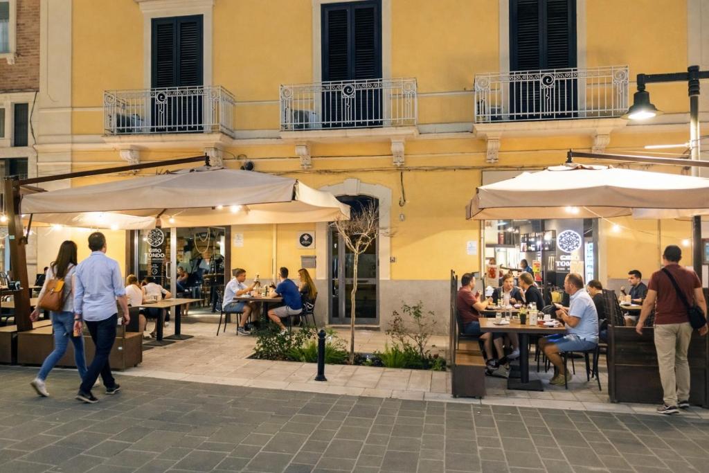 a group of people sitting outside a restaurant with umbrellas at Le Gemme Rooms in Matera