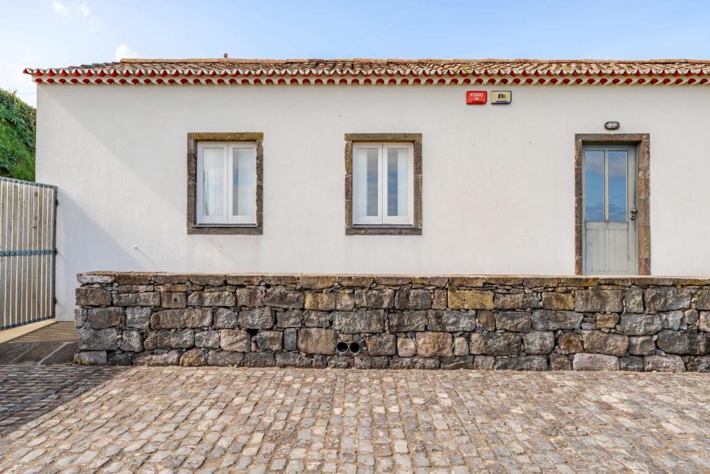 a house with a stone wall and windows at Casas do Forneiro - T1 in Nordeste