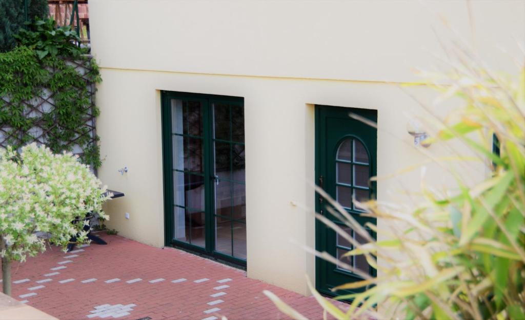a white building with a green door and some plants at Ferienwohnung Karin in Losheim