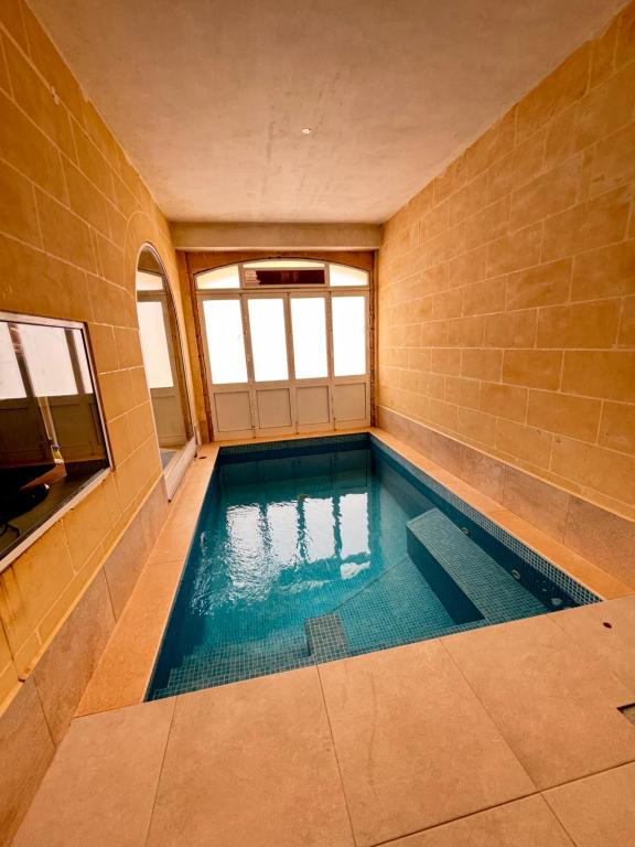a swimming pool in a room with a brick wall at Serenity Wellness Farmhouse With Private Sauna in Nadur