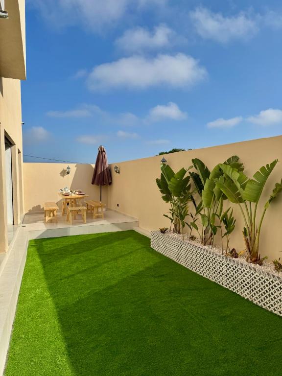 a backyard with green grass and a table on a building at Dar Youba, Luxe Villa Taghazout in Taghazout