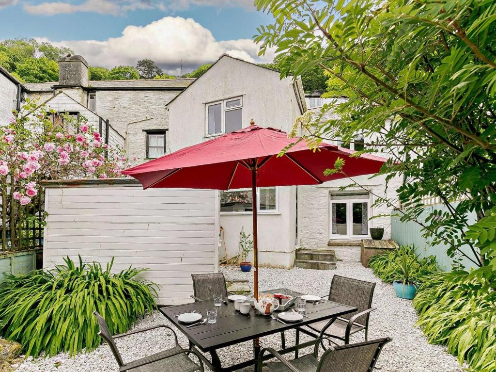 a patio with a table with a red umbrella at 3 Bed in Looe oc-92273 in Polperro