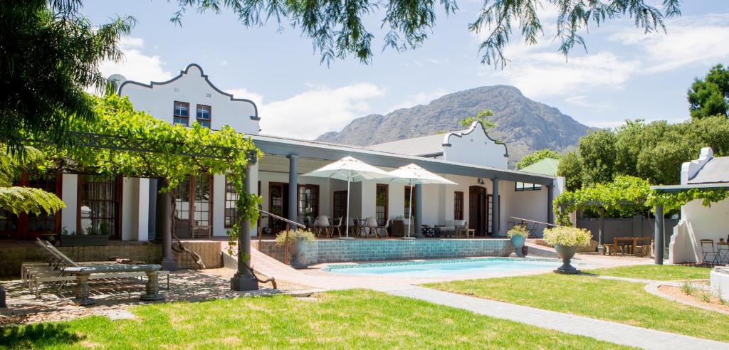 a villa with a swimming pool and mountains in the background at Mont d'Or Franschhoek in Franschhoek