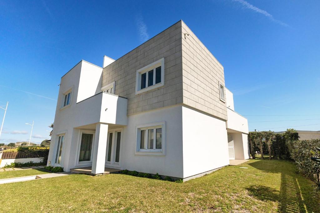 a white house on a lawn with a blue sky at Dunas Das Marinhas in Marinhas