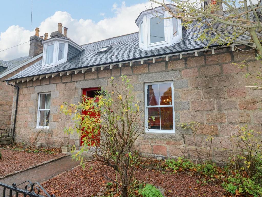 a stone house with a red door and windows at Lindean in Ballater
