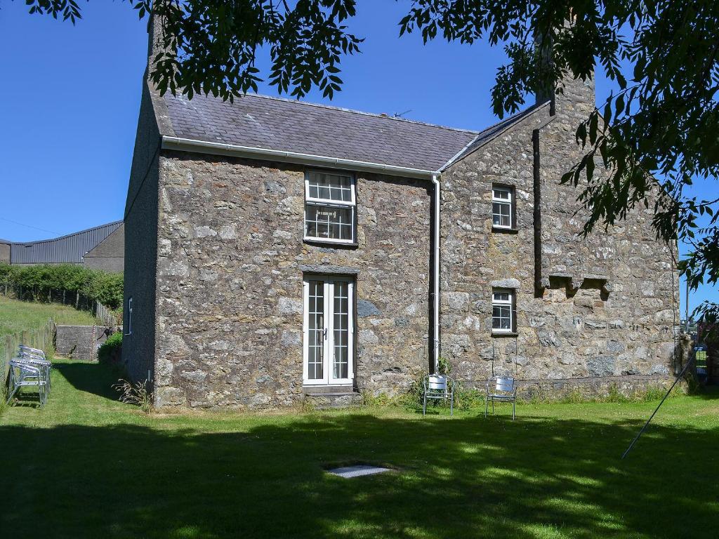 an old stone building with chairs in front of it at Bodwi Isaf in Abersoch