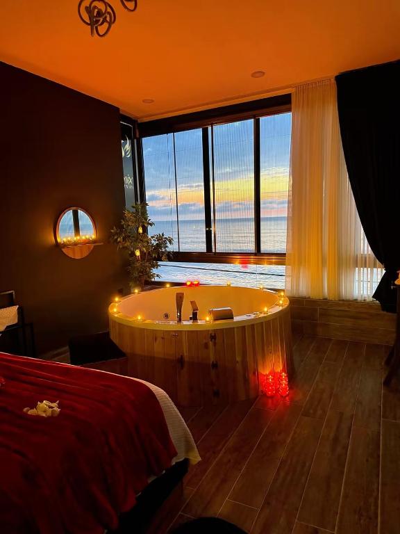 a bedroom with a tub in a room with a large window at Fenix loft in Ardeşen