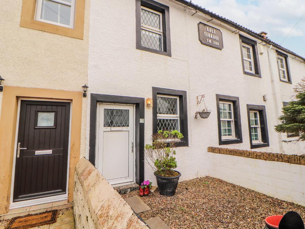 a white house with a black door and windows at 25 Low Seaton in Workington