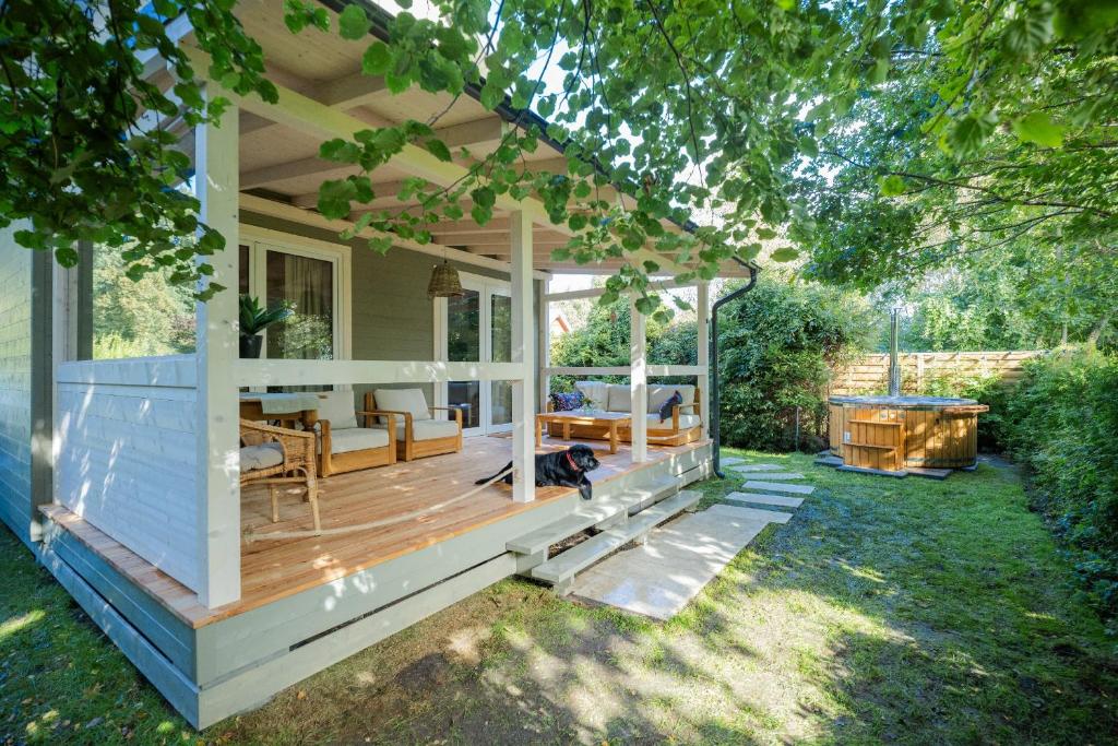 a house with a porch with a dog sitting on the deck at Krukówka Białogóra & jacuzzi in Białogóra