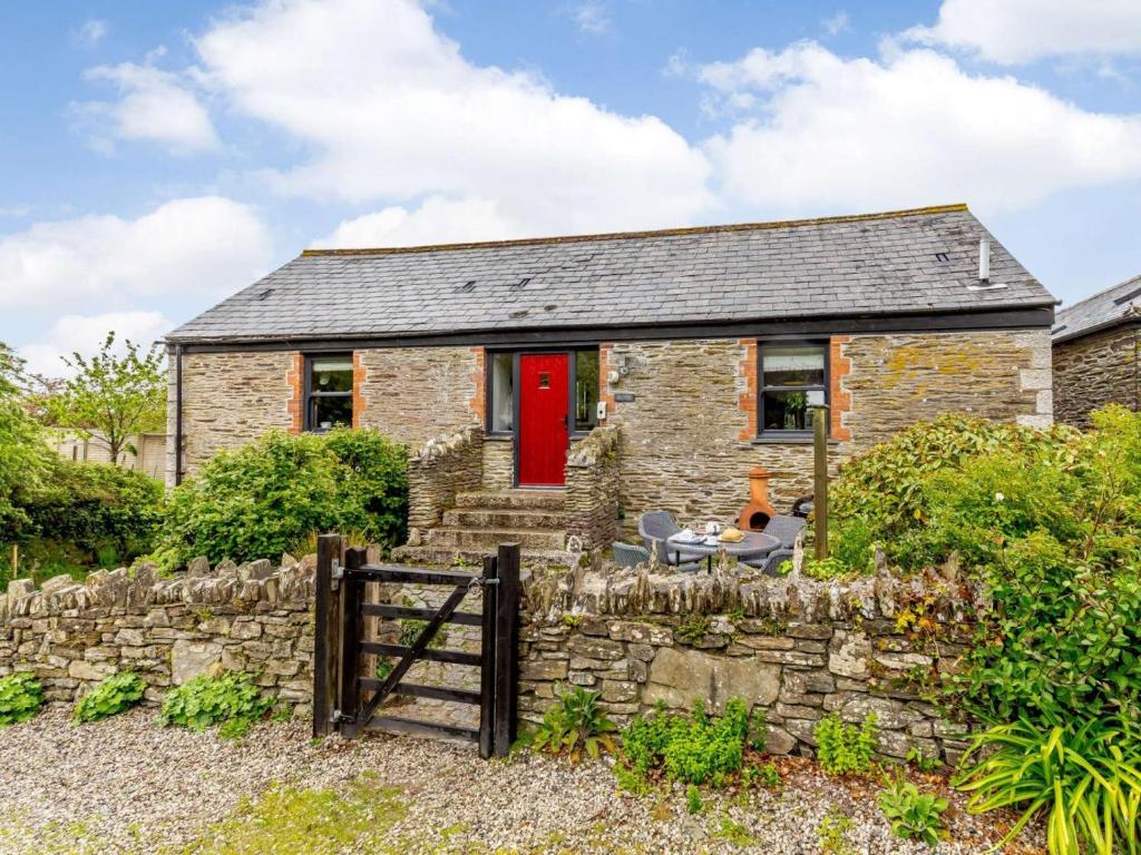 a stone house with a red door and a stone wall at 2 Bed in Fowey oc-55383 in Golant