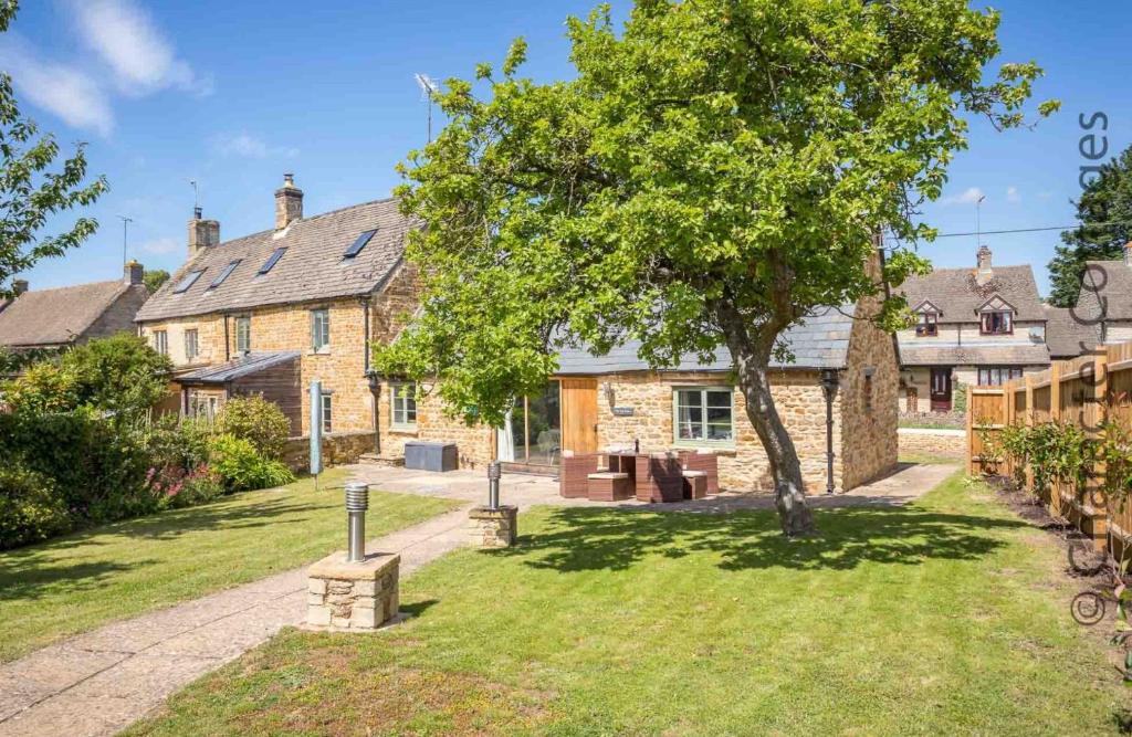a house with a tree in the yard at The Tap Room in Kingham