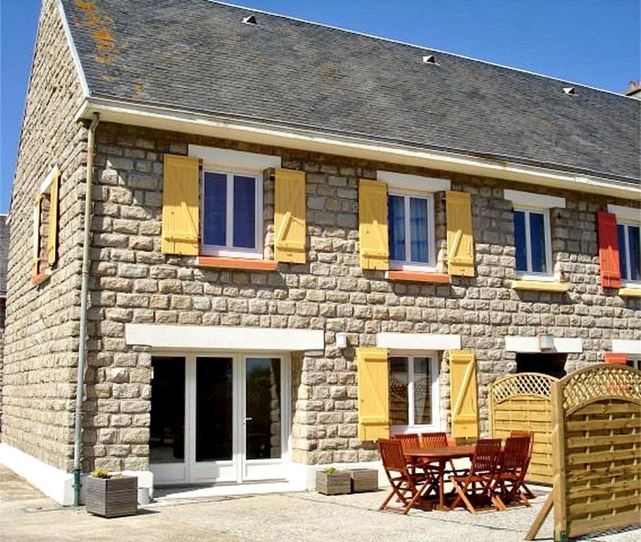 a stone house with chairs and a table in front of it at Villa SURF Situation exceptionnelle à 3 min à pied de la plage de Pors Carn Pour 5 personnes Authentique Bien équipée Jardin & BBQ Parking privatif in Penmarch