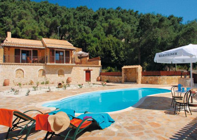 a house with a swimming pool with chairs and an umbrella at Villa Adrianna in Longós