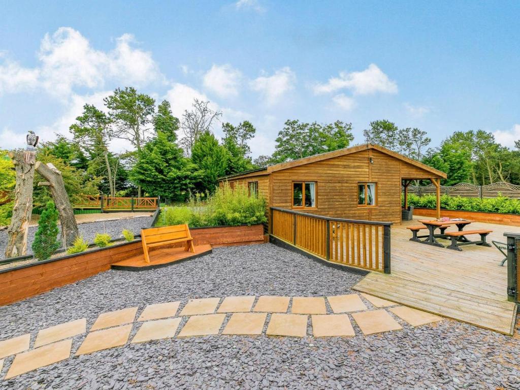 a wooden cabin with a wooden deck and a bench at 2 Bed in Malton oc-87936 in West Heslerton
