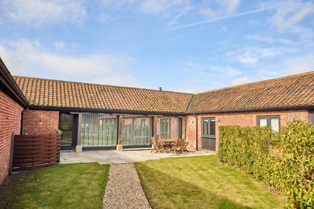a brick house with a patio and a yard at The Saddlery in Norwich