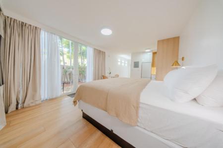 a white bedroom with a large bed and a large window at Green Island Inn in Fort Lauderdale