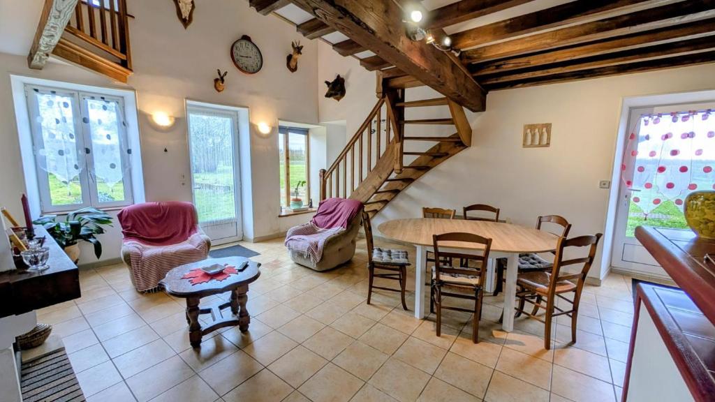 a living room with a table and chairs and a staircase at Chez mamie couture in Bussière-Boffy