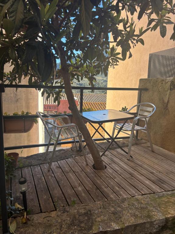 a table and a chair on a deck with a tree at Chambre Le 40 marches in Cucugnan