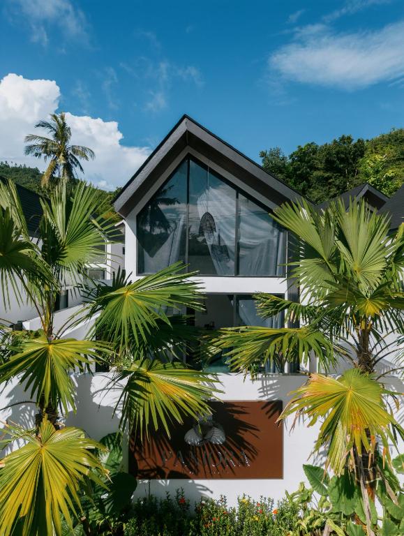 a house with glass windows and palm trees at Paniora Loft Villas in Kuta Lombok