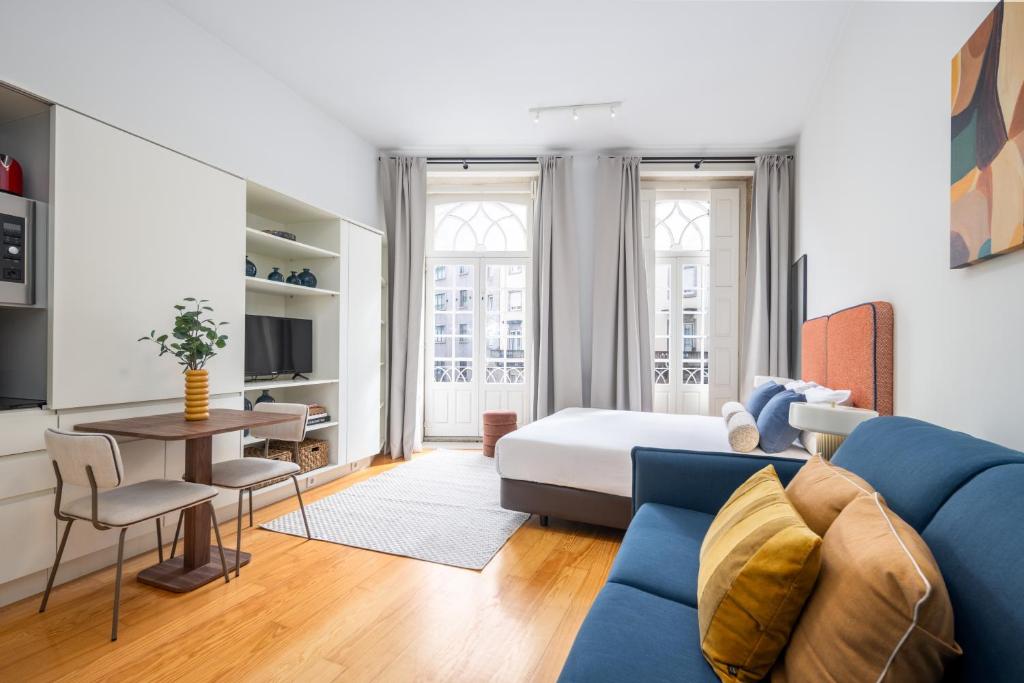 a living room with a blue couch and a bed at Aspasios Trindade Apartments in Porto