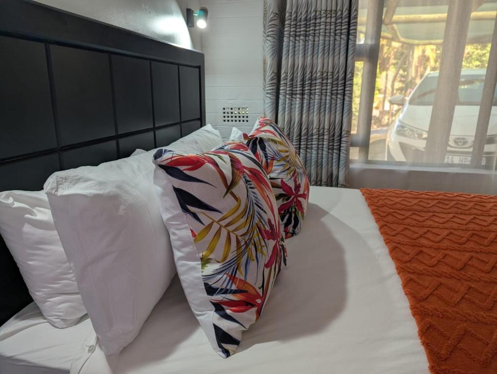 a bed with two pillows and a scarf on it at Carravensiria Chalet 27 in Hibberdene