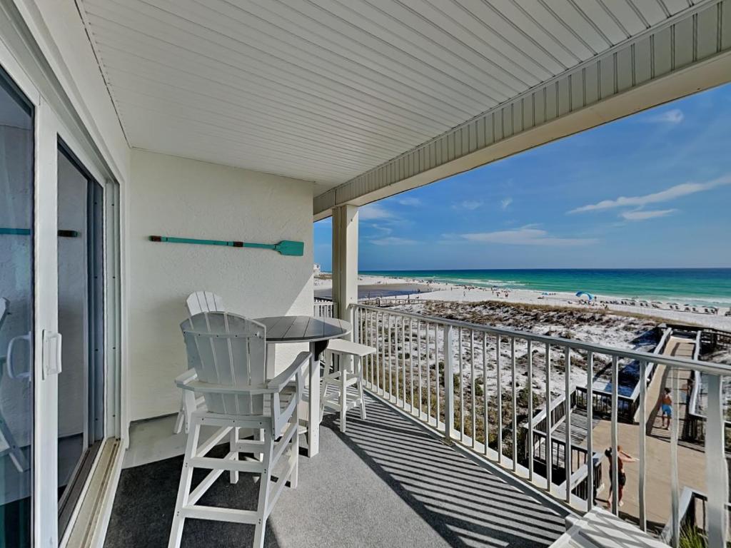 a balcony with a table and chairs and the beach at Commodores Retreat #205 in Santa Rosa Beach