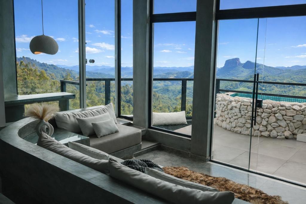 a living room with a couch and a large window at Chalé Boutique - Spa - Sauna seca , Jacuzzi , Rede suspensa in Campos do Jordão