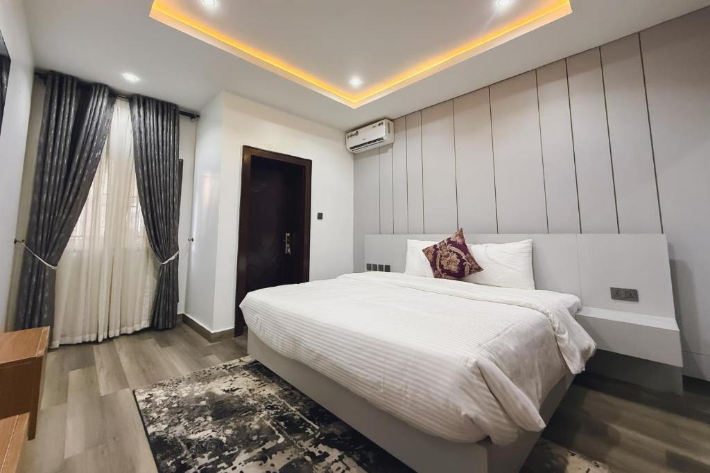 a bedroom with a large white bed and a window at Macdestly Apartments in Abuja