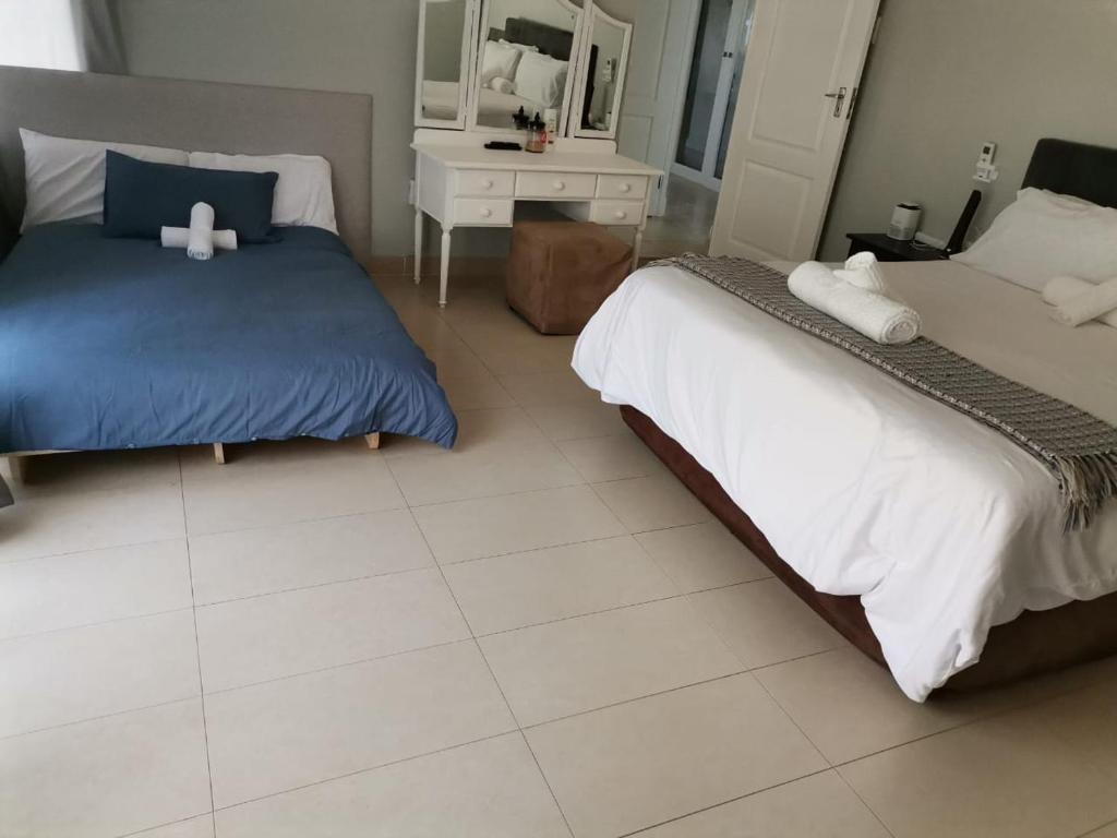 a bedroom with two beds and a white tiled floor at Megs Guesthouse in Ballito