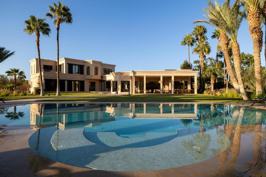 a house with palm trees and a swimming pool at Villa Yliane in Marrakesh
