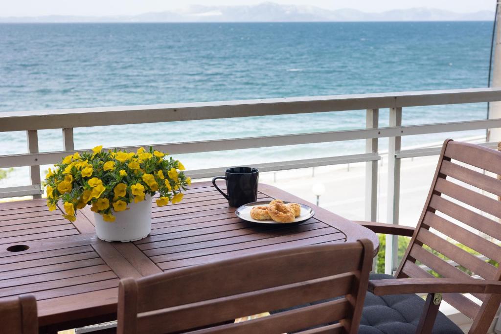 a table with a plate of food and flowers on a balcony at Euphoria Mare in Néa Palátia