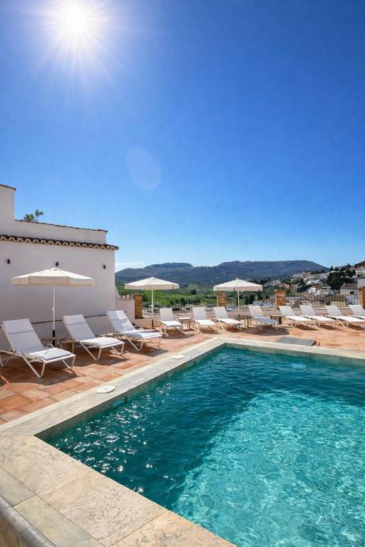a pool with chairs and umbrellas next to a building at Avanel Boutique Apartments in Ronda