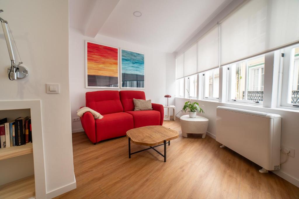 a living room with a red couch and windows at Sarridal, Lar Atlántico in Cedeira