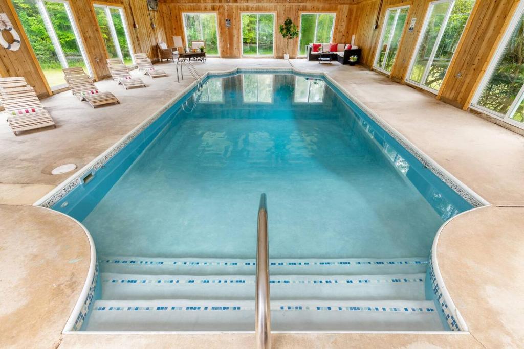 a large swimming pool with stairs in a house at Indoor Pool Poconos Retreat with Arcade in Lake Ariel