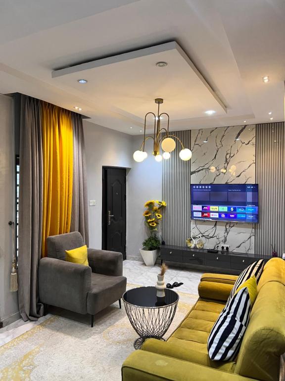 a living room with a yellow couch and a tv at Executive 2-Bedroom Apartment in Ikeja