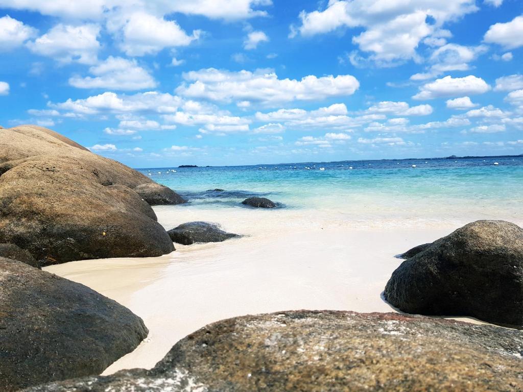 a sandy beach with rocks and the ocean at The zen inn in Nikawatawana