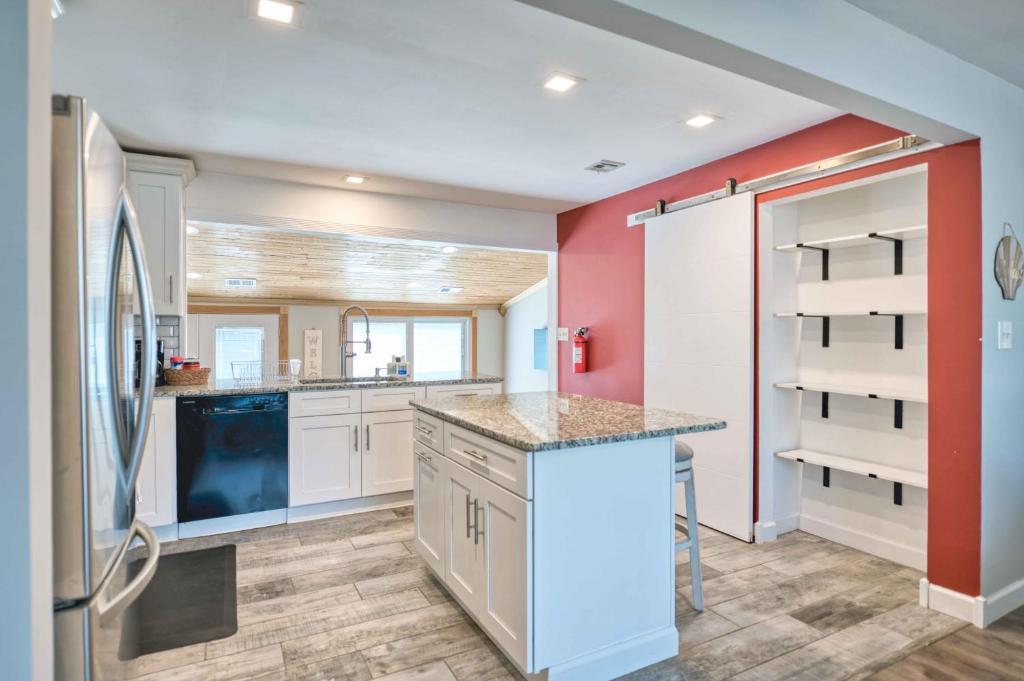 a kitchen with white cabinets and a red wall at Waterfront oasis 3BR Game Room Pet Friendly in Little Egg Harbor Township