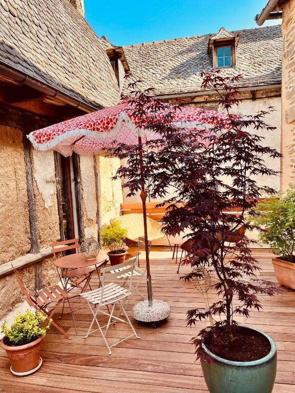 a wooden deck with an umbrella and a table and chairs at la grange d'Eugenie in Estaing