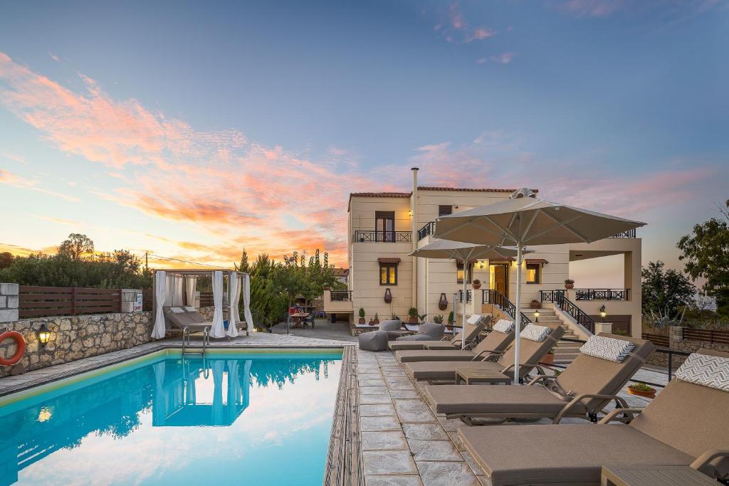a pool with chairs and an umbrella next to a building at Villa Rosemary - Luxury Nature Escape in Roussospítion