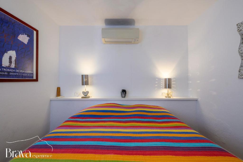 a colorful striped bed in a room with two lamps at Chez Pacha - Dúplex céntrico I 2' playa I hasta 5 huéspedes I equipado I Brava Experience in Cadaqués