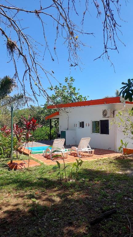 a house with two chairs and a swimming pool at Villas Pura Vida - Mango in Puntarenas